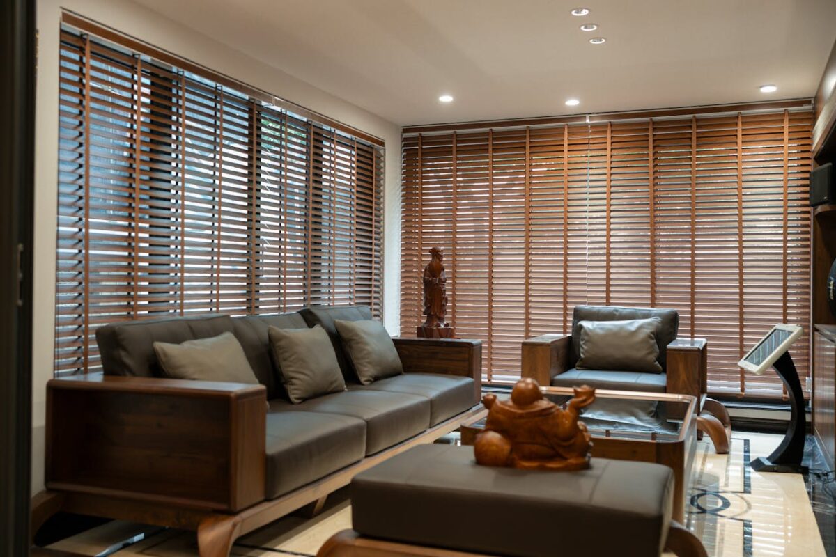 services-03 Elegant living room featuring wooden blinds, cozy furniture, and artistic decor for a warm and inviting ambiance.