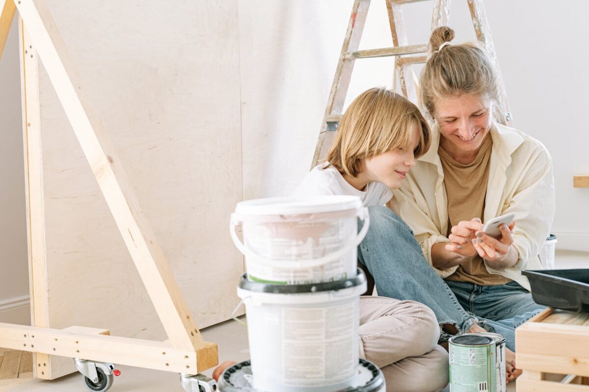 services-02 Mother and son smile while looking at a smartphone during a home renovation project.