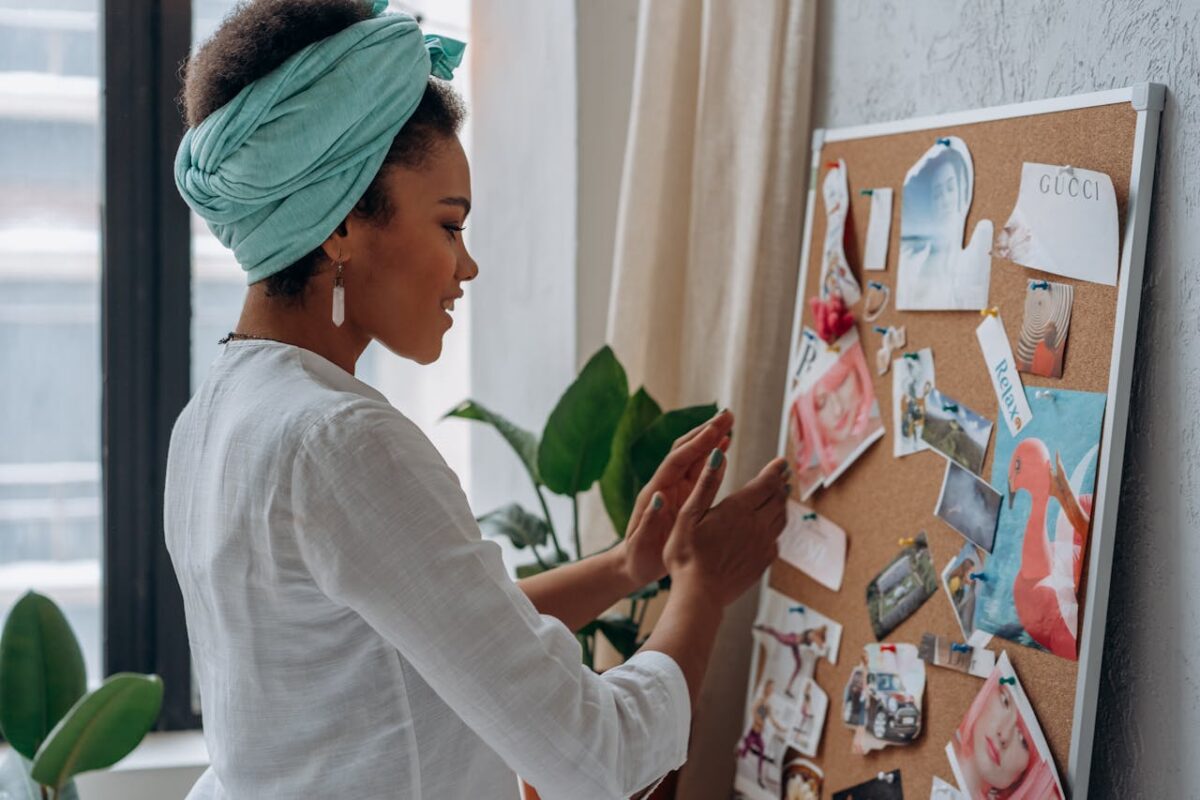 A woman arranging a creative mood board with diverse images and notes in a stylish interior.